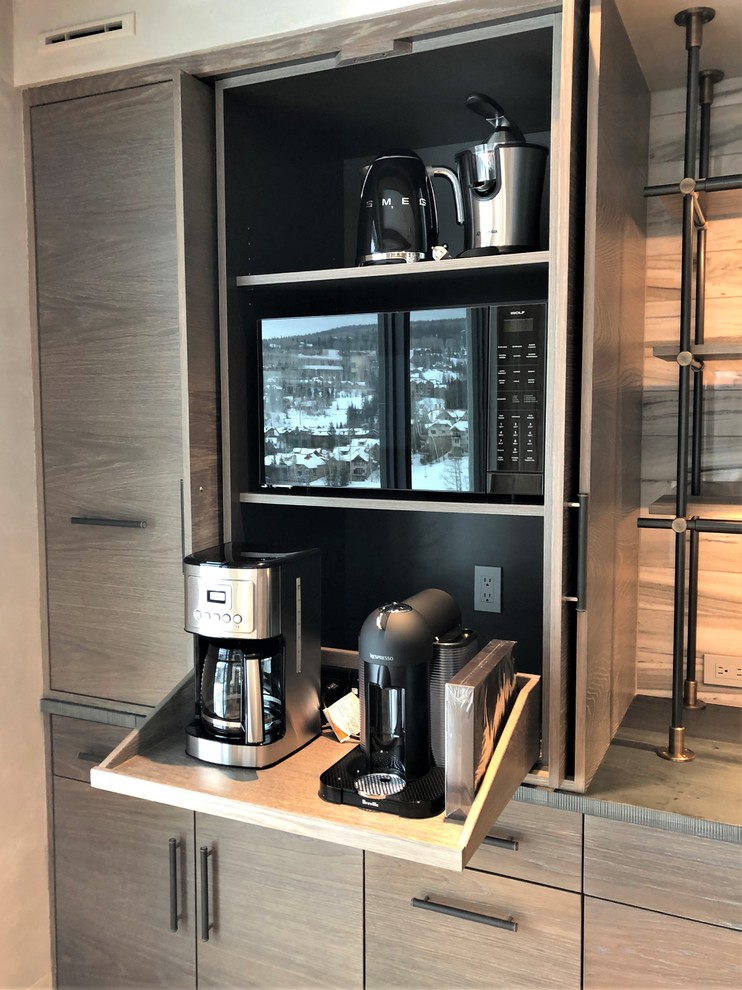 Example of a large trendy u-shaped medium tone wood floor and brown floor eat-in kitchen design in Denver with a farmhouse sink, flat-panel cabinets, light wood cabinets, stainless steel appliances, an island, concrete countertops, gray backsplash, marble backsplash and gray countertops