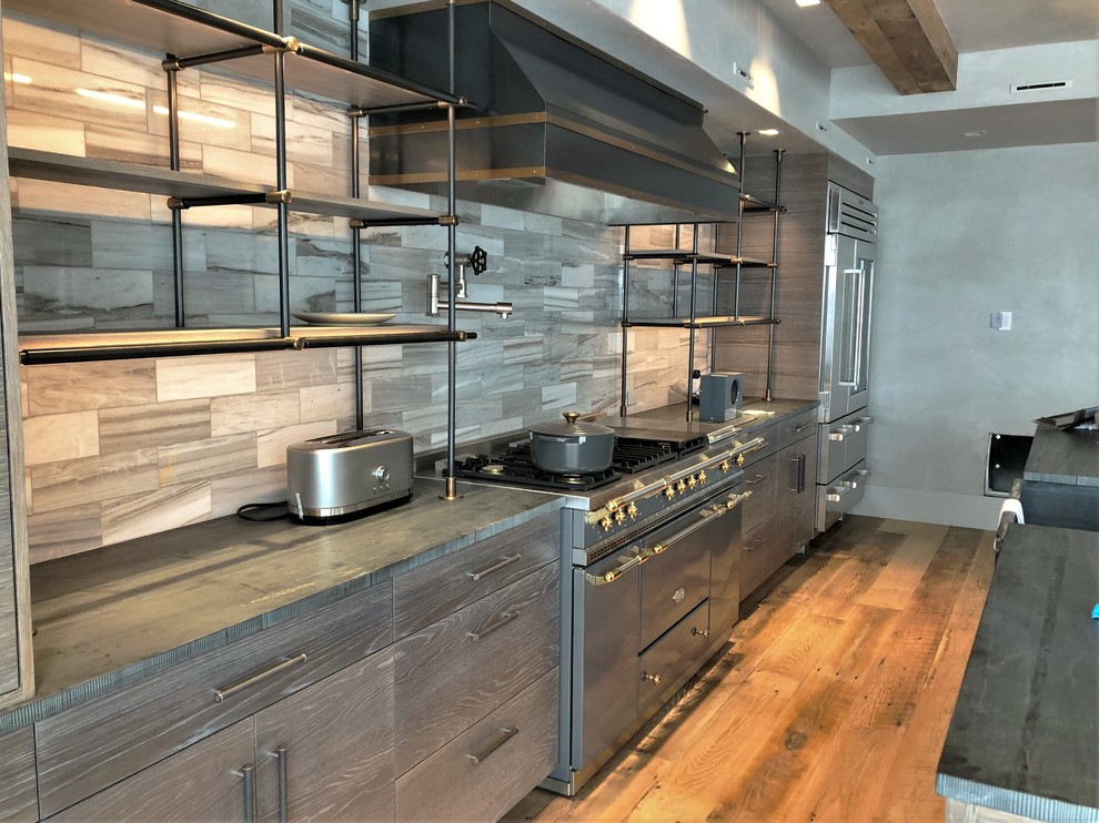 Example of a large trendy u-shaped medium tone wood floor and brown floor eat-in kitchen design in Denver with a farmhouse sink, flat-panel cabinets, light wood cabinets, quartzite countertops, beige backsplash, porcelain backsplash, stainless steel appliances, an island and black countertops