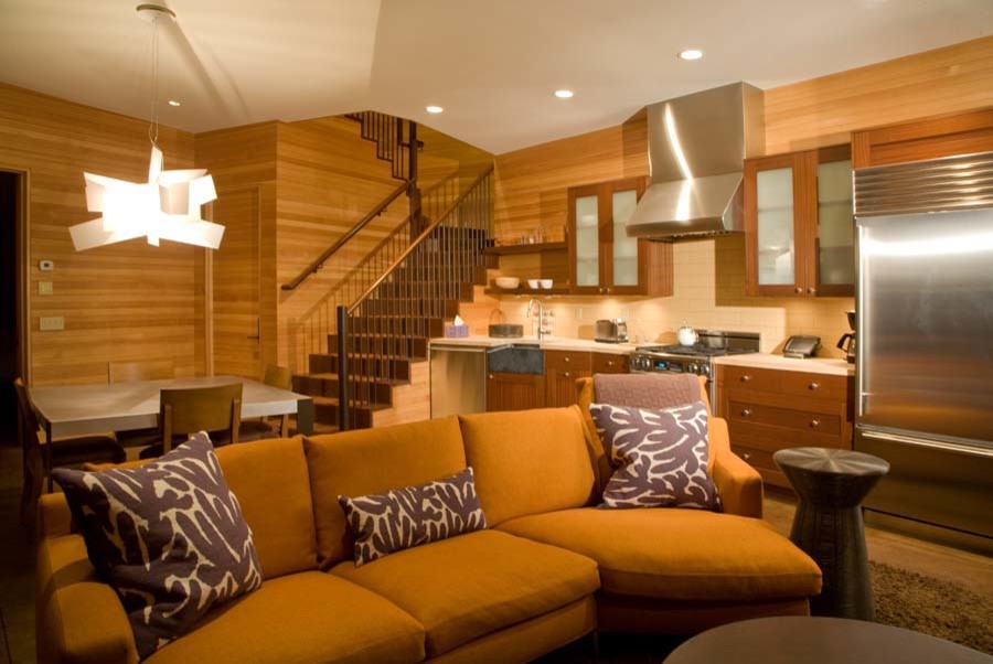 Cette photo montre une petite cuisine ouverte linéaire tendance en bois brun avec un placard à porte plane, un électroménager en acier inoxydable et un sol en bois brun.