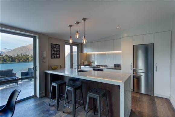 Exempel på ett modernt linjärt kök och matrum, med en rustik diskho, släta luckor, vita skåp, granitbänkskiva, vitt stänkskydd, glaspanel som stänkskydd, rostfria vitvaror, mörkt trägolv, en köksö och brunt golv