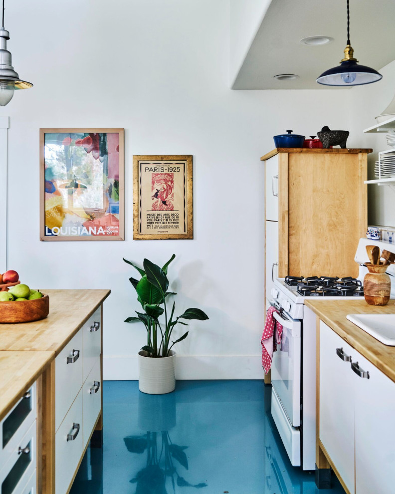 Inspiration for a large shabby-chic style galley kitchen/diner in Salt Lake City with a built-in sink, flat-panel cabinets, white cabinets, wood worktops, white appliances, concrete flooring, an island, blue floors and brown worktops.