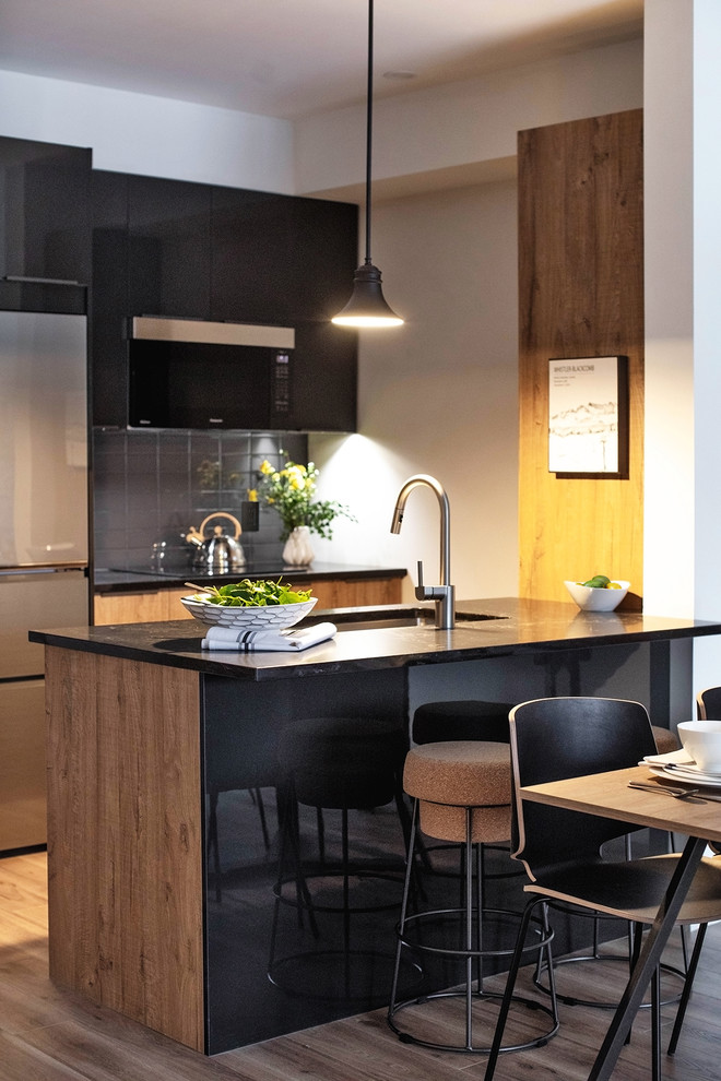 Inspiration for a small modern galley open plan kitchen in Toronto with flat-panel cabinets, distressed cabinets, engineered stone countertops, black splashback, metro tiled splashback, coloured appliances, laminate floors, a breakfast bar, brown floors and black worktops.