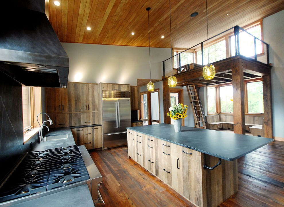 Inspiration for a huge industrial multicolored floor eat-in kitchen remodel in Burlington with an undermount sink, flat-panel cabinets, medium tone wood cabinets, soapstone countertops, black backsplash, stone slab backsplash, stainless steel appliances and an island