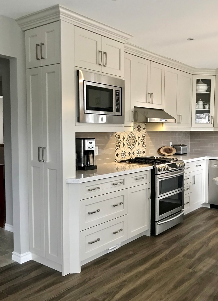 Bild på ett litet vintage vit vitt kök, med en undermonterad diskho, luckor med profilerade fronter, grå skåp, bänkskiva i kvartsit, stänkskydd i keramik, rostfria vitvaror, laminatgolv, en köksö och brunt golv