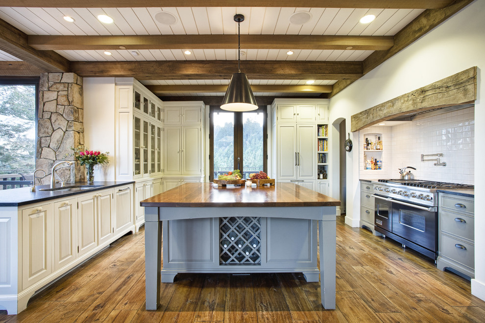 Mountain style u-shaped medium tone wood floor kitchen photo in San Francisco with an island, an undermount sink, raised-panel cabinets, white cabinets, white backsplash and stainless steel appliances