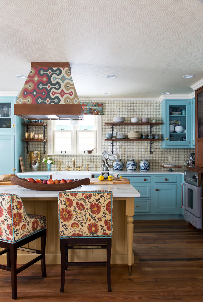 This is an example of an eclectic l-shaped kitchen in Denver with a belfast sink, shaker cabinets, blue cabinets, beige splashback, dark hardwood flooring and an island.