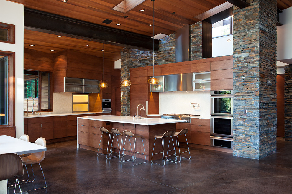 Cette image montre une cuisine ouverte design en bois foncé avec un placard à porte plane, un électroménager en acier inoxydable et un sol marron.