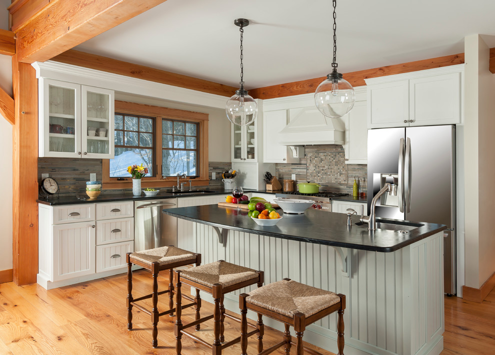 Eat-in kitchen - mid-sized rustic l-shaped medium tone wood floor eat-in kitchen idea in Burlington with white cabinets, granite countertops, multicolored backsplash, an island, an undermount sink, recessed-panel cabinets, stone tile backsplash and stainless steel appliances