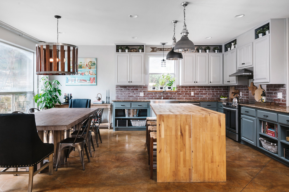 Bild på ett lantligt brun brunt kök, med en rustik diskho, luckor med upphöjd panel, grå skåp, träbänkskiva, rött stänkskydd, stänkskydd i tegel, rostfria vitvaror, betonggolv, en köksö och brunt golv
