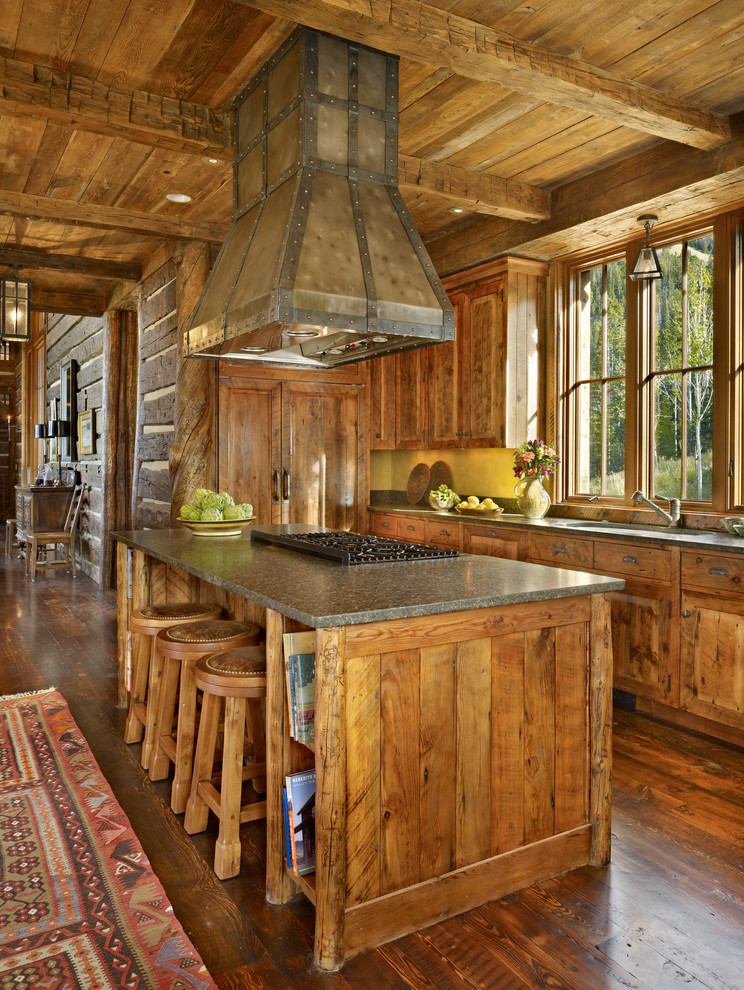 Mittelgroße Urige Wohnküche mit hellbraunen Holzschränken, Granit-Arbeitsplatte, braunem Holzboden, profilierten Schrankfronten, Rückwand aus Backstein und Kücheninsel in Sonstige