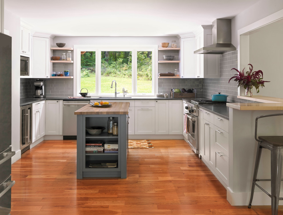 Exempel på ett mellanstort klassiskt grå grått u-kök, med granitbänkskiva, grått stänkskydd, rostfria vitvaror, en köksö, skåp i shakerstil, vita skåp, stänkskydd i tunnelbanekakel och mellanmörkt trägolv