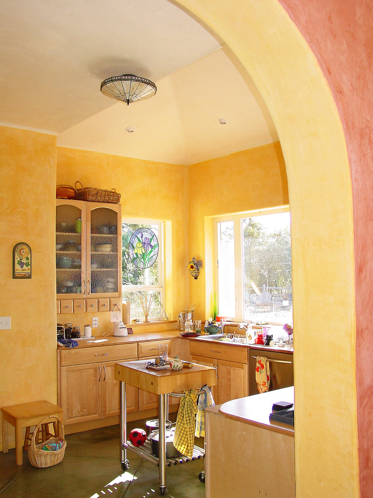 Пример оригинального дизайна: маленькая отдельная, п-образная кухня в средиземноморском стиле с врезной мойкой, фасадами с утопленной филенкой, светлыми деревянными фасадами, гранитной столешницей, техникой из нержавеющей стали, бетонным полом, островом, серым полом, желтым фартуком и коричневой столешницей для на участке и в саду