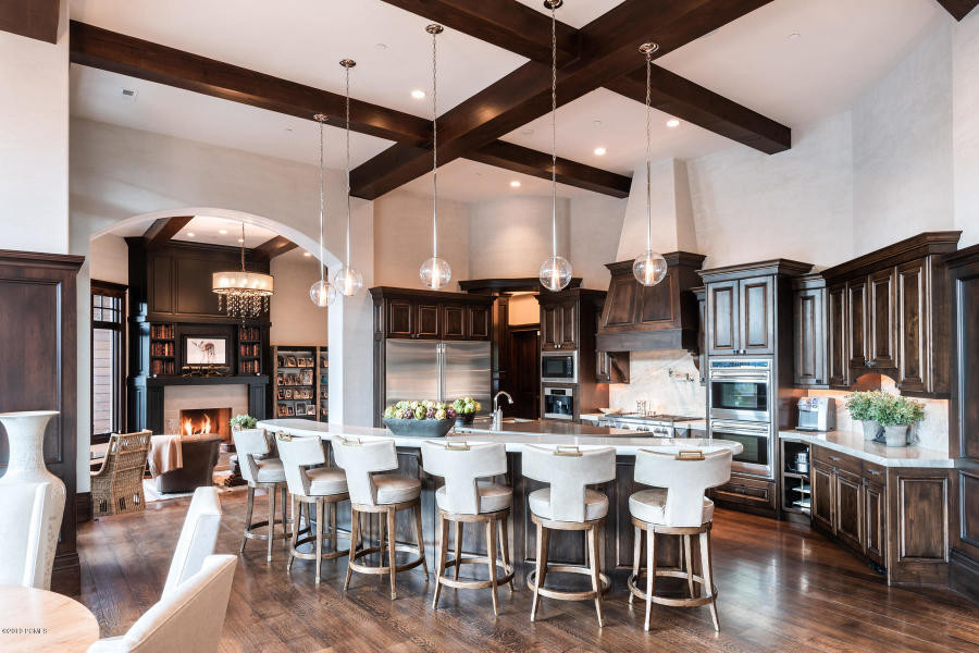 Inspiration for a large transitional l-shaped dark wood floor and brown floor eat-in kitchen remodel in Salt Lake City with a farmhouse sink, raised-panel cabinets, dark wood cabinets, limestone countertops, white backsplash, stone slab backsplash, stainless steel appliances, two islands and white countertops