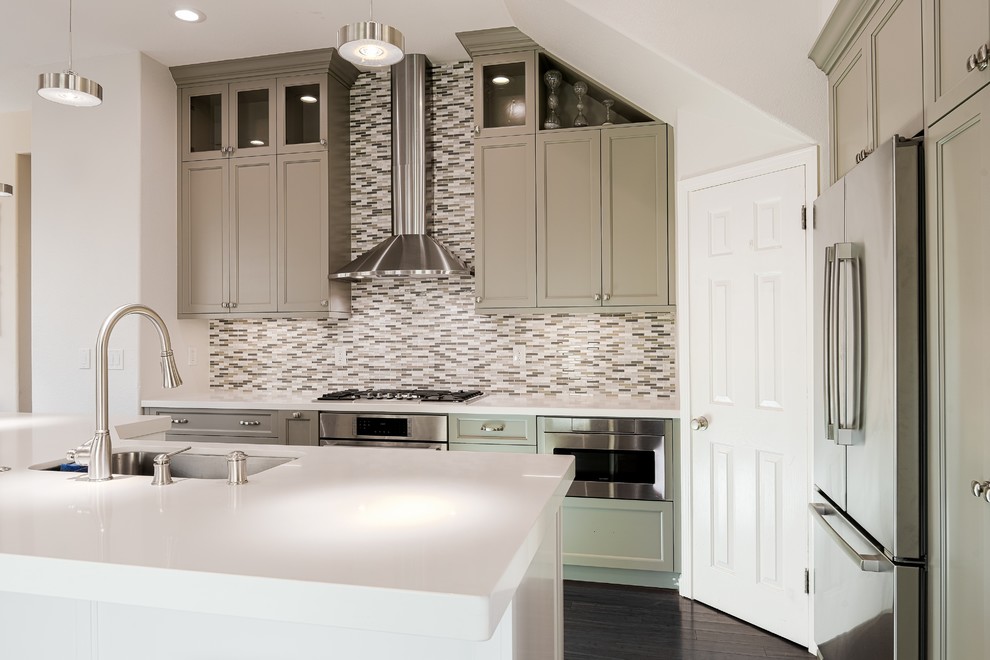 Photo of a large classic l-shaped kitchen/diner in San Francisco with grey cabinets, multi-coloured splashback, stainless steel appliances, an island, a built-in sink, beaded cabinets, granite worktops, matchstick tiled splashback, medium hardwood flooring, brown floors and white worktops.