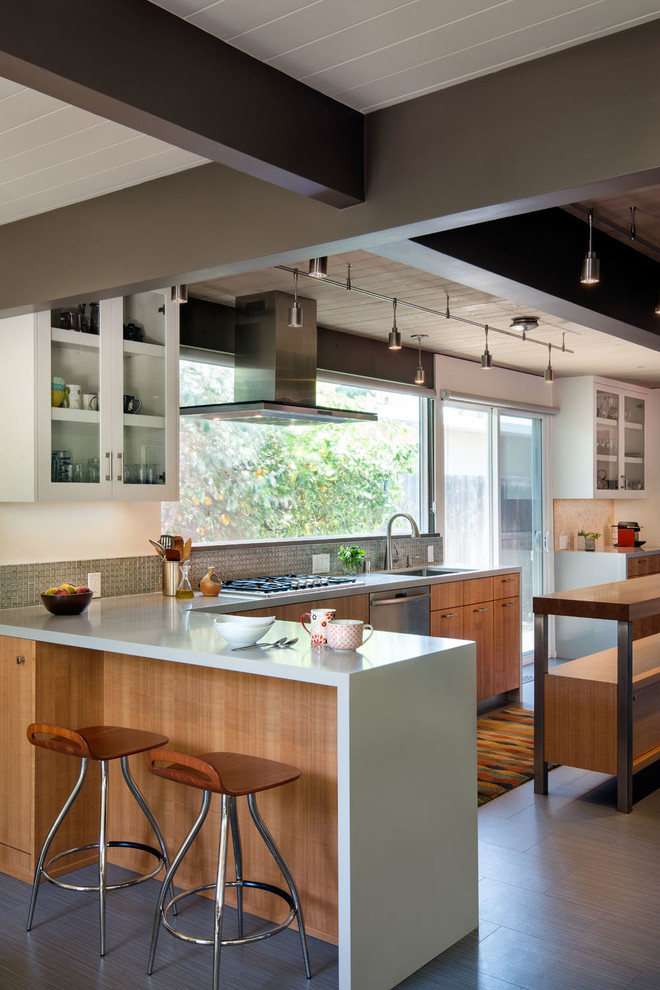 Inspiration for a large contemporary galley laminate floor and brown floor eat-in kitchen remodel in San Francisco with a single-bowl sink, flat-panel cabinets, light wood cabinets, solid surface countertops, gray backsplash, mosaic tile backsplash, stainless steel appliances and an island