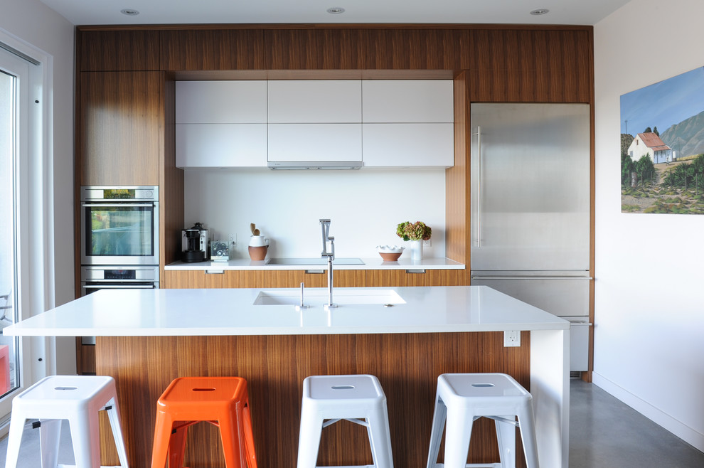 Inspiration for a small contemporary galley concrete floor and gray floor kitchen remodel in Vancouver with flat-panel cabinets, medium tone wood cabinets, white backsplash, stainless steel appliances, an island and a single-bowl sink