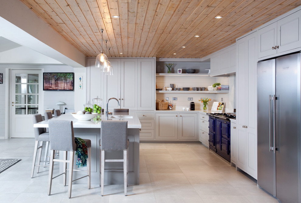 This is an example of a traditional l-shaped open plan kitchen in Dublin with a submerged sink, recessed-panel cabinets, beige cabinets, beige splashback, wood splashback, coloured appliances, an island and beige floors.