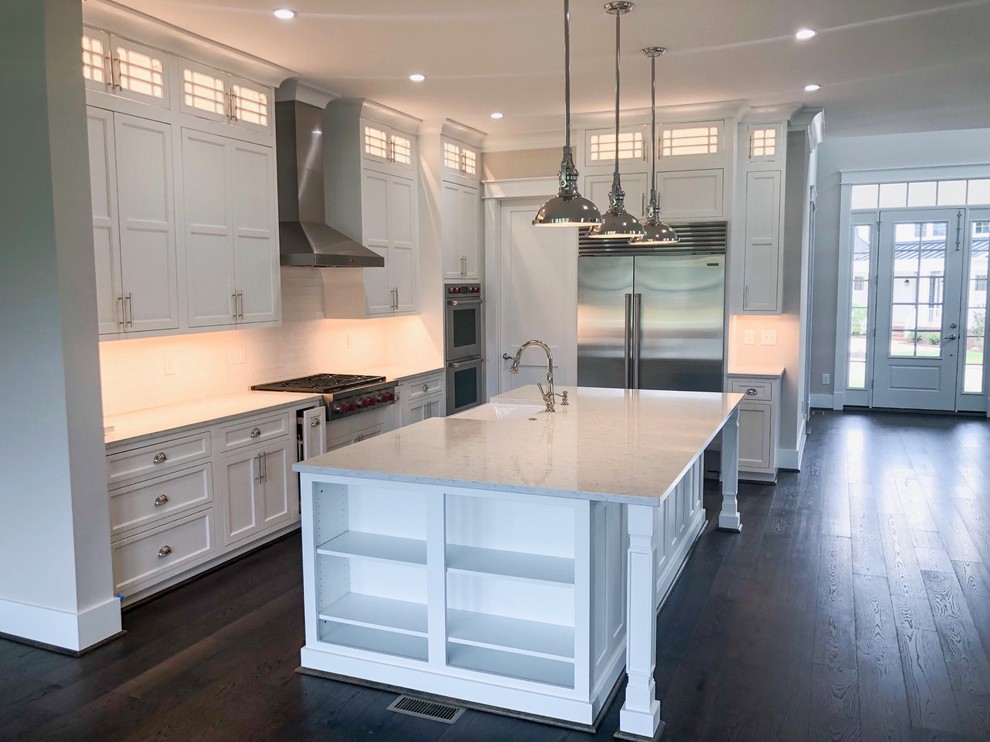 Inspiration for a mid-sized transitional l-shaped dark wood floor and gray floor enclosed kitchen remodel in Richmond with a farmhouse sink, recessed-panel cabinets, white cabinets, quartz countertops, white backsplash, subway tile backsplash, stainless steel appliances, an island and gray countertops
