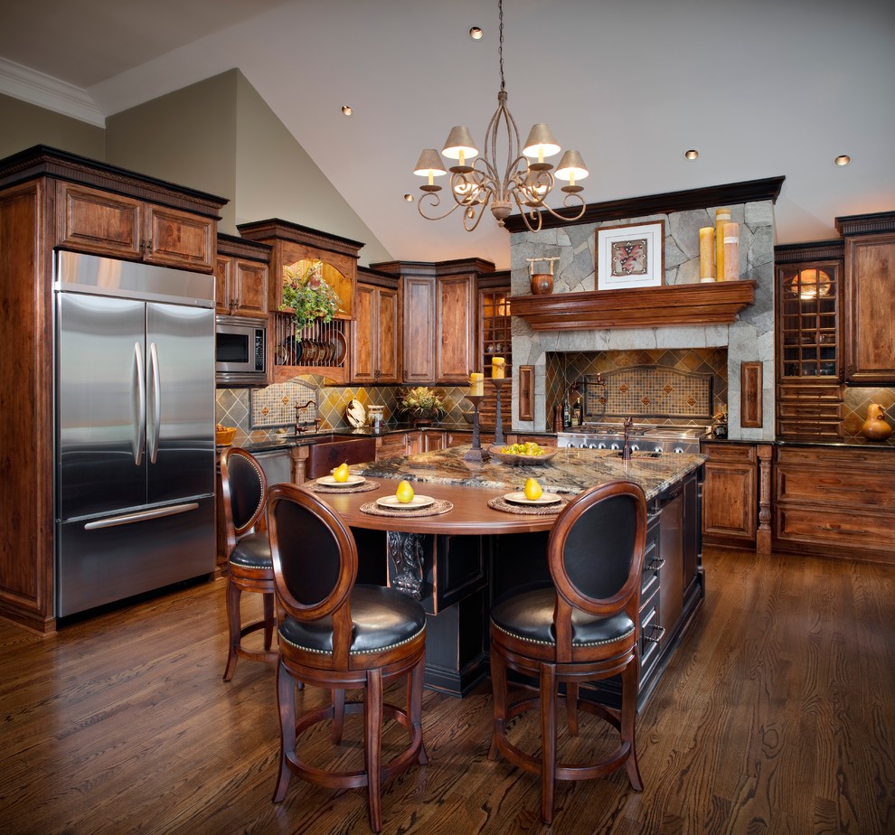 Bild på ett mellanstort rustikt kök, med en rustik diskho, luckor med upphöjd panel, skåp i mörkt trä, flerfärgad stänkskydd, rostfria vitvaror, mörkt trägolv, en köksö, stänkskydd i skiffer, granitbänkskiva och brunt golv