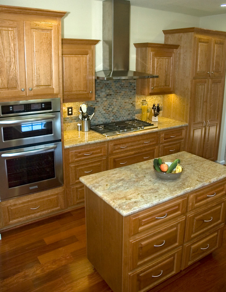 Esempio di una cucina classica con lavello sottopiano, ante con bugna sagomata, ante in legno scuro, top in granito, paraspruzzi grigio e elettrodomestici in acciaio inossidabile