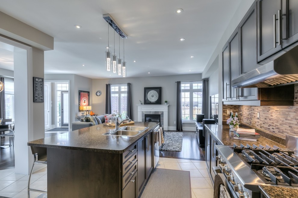 Medium sized modern l-shaped open plan kitchen in Toronto with shaker cabinets, dark wood cabinets, stainless steel appliances, dark hardwood flooring and an island.