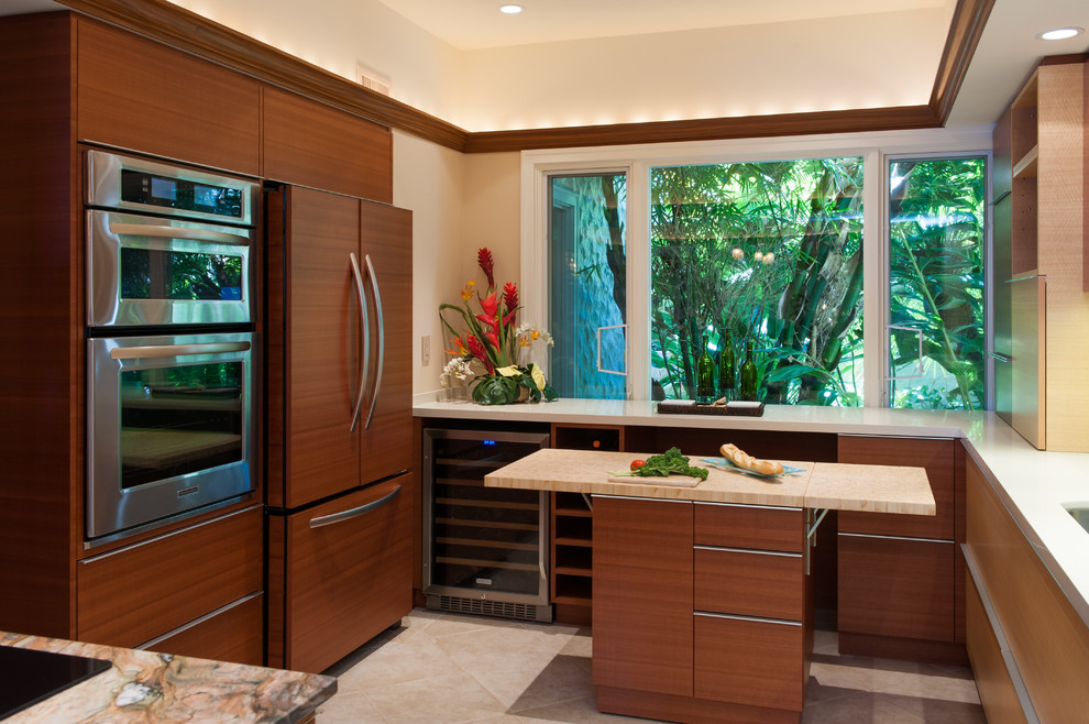 Bild på ett tropiskt kök, med en enkel diskho, släta luckor, skåp i mellenmörkt trä, bänkskiva i kvartsit, rött stänkskydd, stänkskydd i glaskakel, integrerade vitvaror, klinkergolv i porslin och flera köksöar