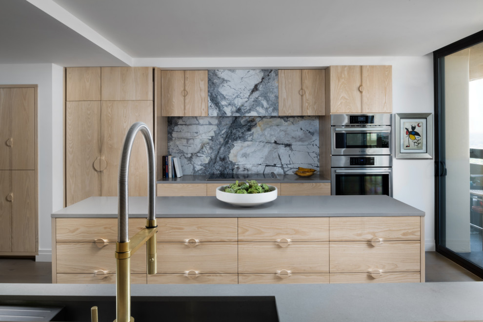 Foto di una cucina contemporanea con lavello sottopiano, ante lisce, ante in legno chiaro, elettrodomestici in acciaio inossidabile, parquet scuro, pavimento marrone e top grigio