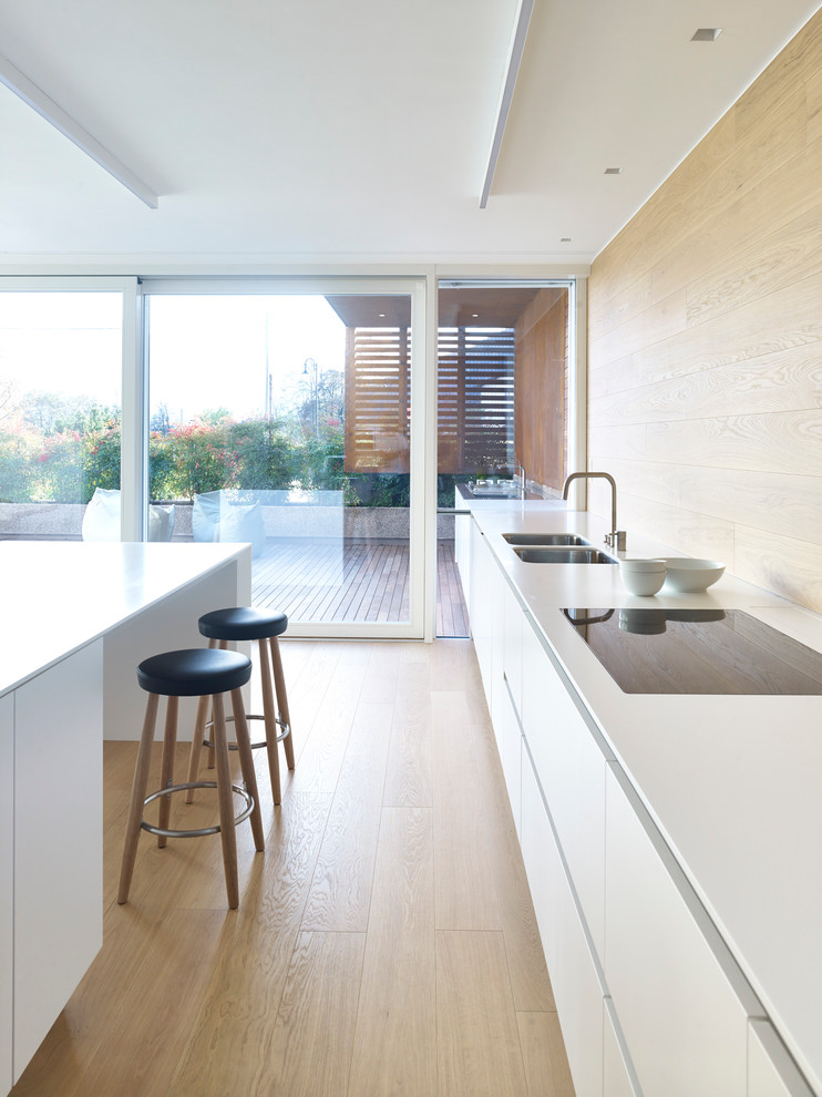 Источник вдохновения для домашнего уюта: параллельная кухня в современном стиле с обеденным столом, плоскими фасадами, белыми фасадами, светлым паркетным полом и островом