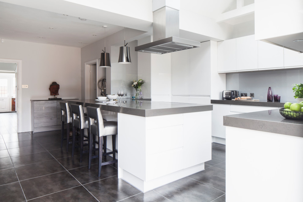 Design ideas for a medium sized contemporary l-shaped kitchen/diner in Sussex with white cabinets, engineered stone countertops, black appliances, a breakfast bar and grey worktops.