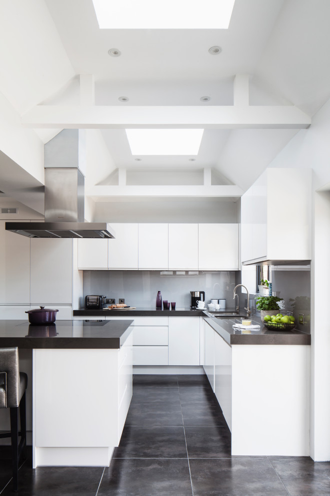 Modern inredning av ett mellanstort grå grått kök, med vita skåp, bänkskiva i kvarts, svarta vitvaror och en halv köksö