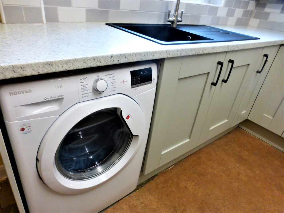 Modelo de lavadero en L tradicional con armarios estilo shaker, puertas de armario grises y encimera de laminado
