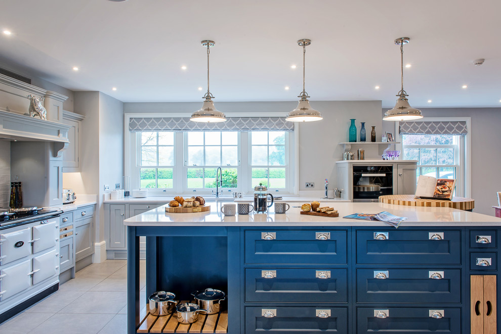 Large traditional open plan kitchen in Surrey with shaker cabinets, blue cabinets, quartz worktops, white splashback, stainless steel appliances, porcelain flooring, an island and grey floors.