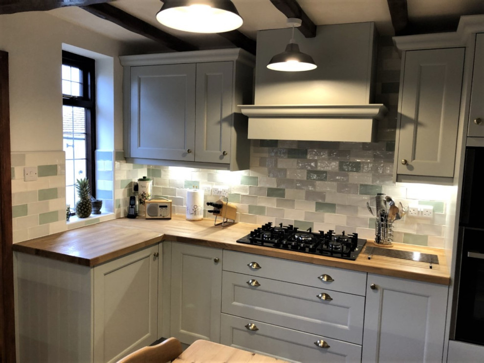 Design ideas for a classic u-shaped kitchen in West Midlands with a belfast sink, shaker cabinets, grey cabinets, multi-coloured splashback, porcelain splashback, black appliances, no island and wood worktops.