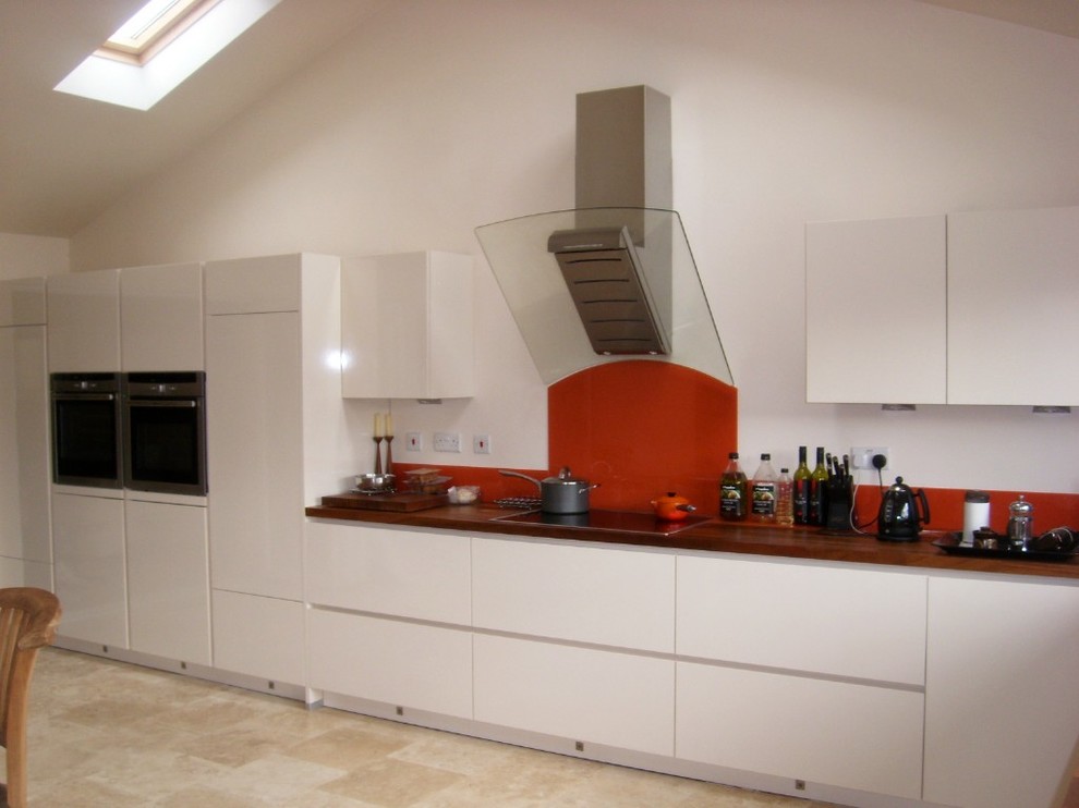 Idee per una cucina abitabile contemporanea con paraspruzzi arancione, paraspruzzi con lastra di vetro e elettrodomestici in acciaio inossidabile