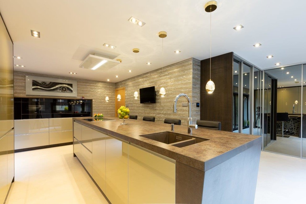 This is an example of a medium sized contemporary enclosed kitchen in Manchester with a submerged sink, glass-front cabinets, beige cabinets, composite countertops, black appliances, porcelain flooring, an island, beige floors and brown worktops.