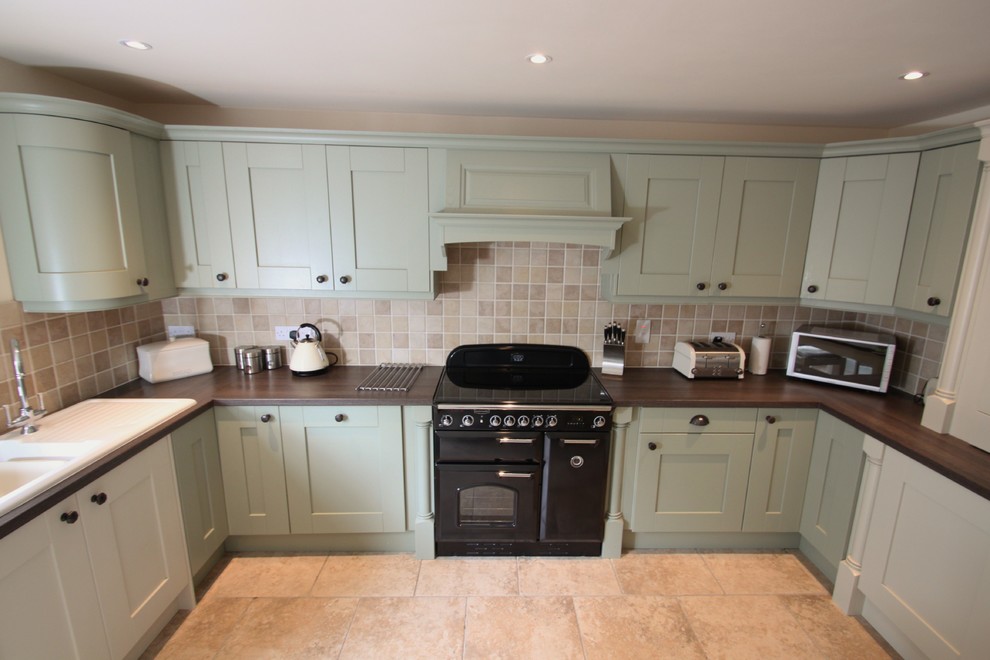 Photo of a large classic u-shaped kitchen/diner in Other with a built-in sink, recessed-panel cabinets, green cabinets, laminate countertops, beige splashback, ceramic splashback, black appliances, ceramic flooring and no island.