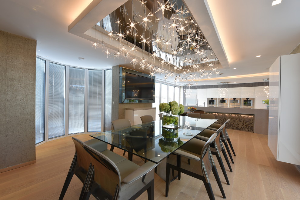 Immagine di un'ampia sala da pranzo aperta verso la cucina minimal con parquet chiaro