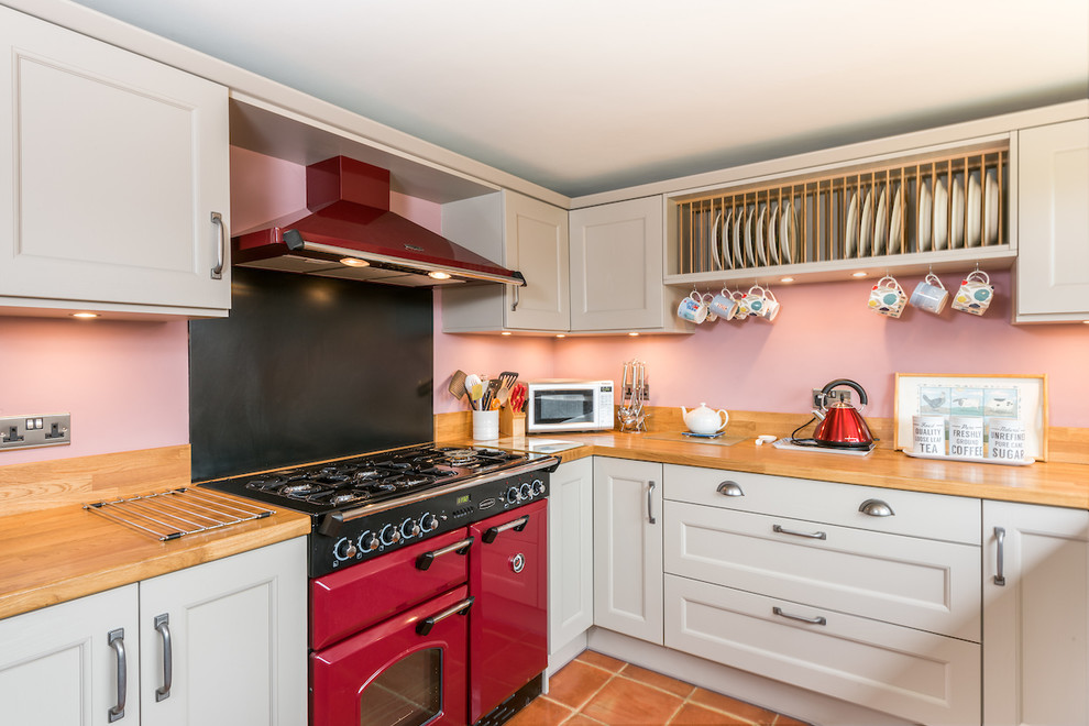 Inspiration for a traditional l-shaped kitchen in Other with recessed-panel cabinets, beige cabinets, wood worktops, pink splashback, coloured appliances, terracotta flooring and orange floors.