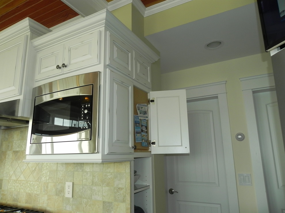 This is an example of a nautical l-shaped kitchen in Providence with a submerged sink, raised-panel cabinets, white cabinets, beige splashback, stainless steel appliances, dark hardwood flooring and no island.