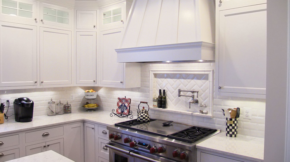 Large traditional l-shaped kitchen pantry in Baltimore with a belfast sink, raised-panel cabinets, white cabinets, engineered stone countertops, white splashback, porcelain splashback, stainless steel appliances, dark hardwood flooring and an island.