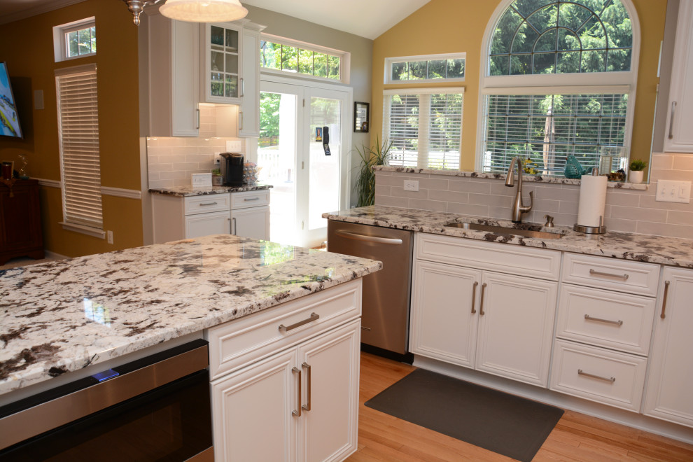 Idéer för ett mellanstort klassiskt vit kök, med en undermonterad diskho, luckor med infälld panel, vita skåp, granitbänkskiva, grått stänkskydd, rostfria vitvaror, ljust trägolv, en köksö och brunt golv