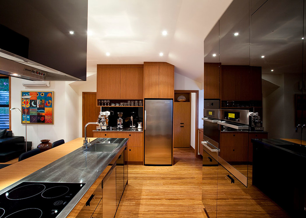 Foto di una cucina design con lavello integrato, ante lisce, ante nere, top in acciaio inossidabile, elettrodomestici neri e penisola