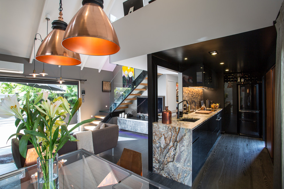 Mid-sized urban galley dark wood floor open concept kitchen photo in Auckland with a single-bowl sink, black cabinets, granite countertops, brown backsplash, mosaic tile backsplash, black appliances and no island