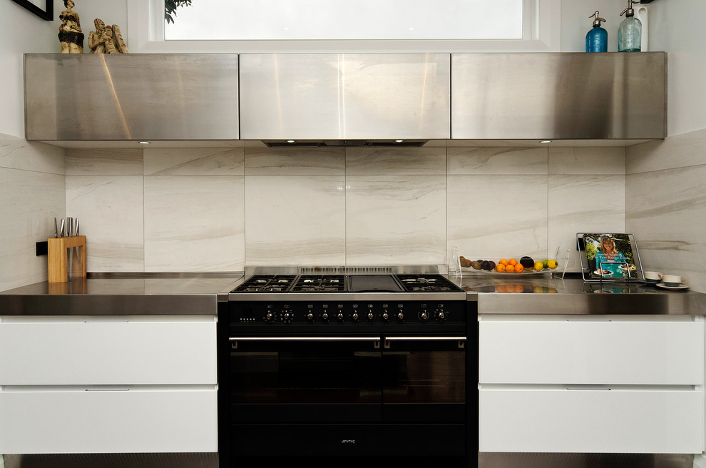 Foto di una cucina contemporanea di medie dimensioni con lavello sottopiano, ante lisce, ante nere, top in superficie solida, paraspruzzi grigio, paraspruzzi con piastrelle in pietra, elettrodomestici neri e parquet scuro