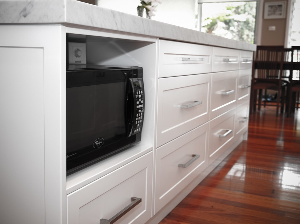 Design ideas for a large classic galley kitchen/diner in Wollongong with a double-bowl sink, shaker cabinets, white cabinets, marble worktops, white splashback, ceramic splashback, stainless steel appliances, medium hardwood flooring and an island.