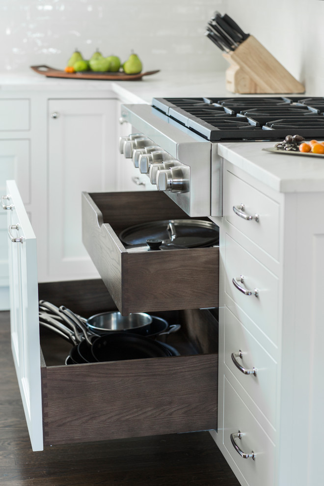 Example of a large classic l-shaped dark wood floor eat-in kitchen design in New York with shaker cabinets, white cabinets, marble countertops, white backsplash, ceramic backsplash, paneled appliances and an island