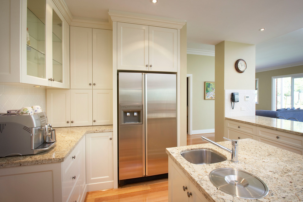 Example of a classic kitchen design in Perth with an undermount sink, shaker cabinets, white cabinets, granite countertops, white backsplash, porcelain backsplash, stainless steel appliances, an island and multicolored countertops