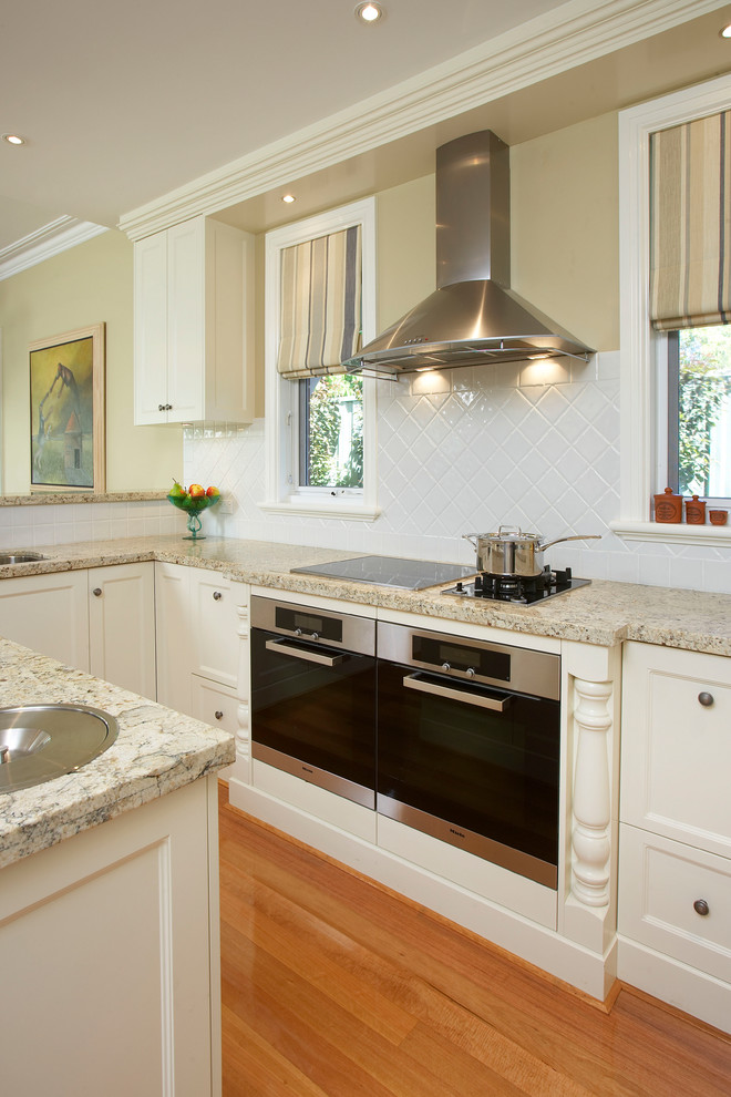 Inredning av ett klassiskt flerfärgad flerfärgat kök, med skåp i shakerstil, vita skåp, granitbänkskiva, vitt stänkskydd, stänkskydd i porslinskakel, rostfria vitvaror och en köksö
