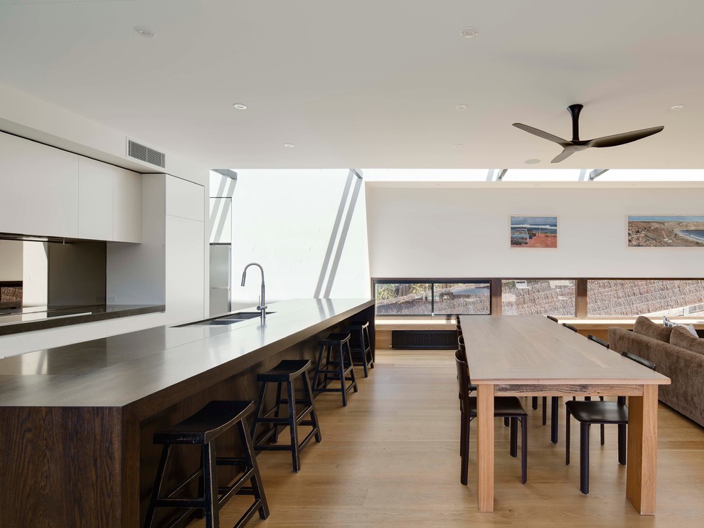 Example of a large trendy galley light wood floor eat-in kitchen design in Melbourne with an undermount sink, flat-panel cabinets, dark wood cabinets, marble countertops, metallic backsplash, mirror backsplash, stainless steel appliances and an island