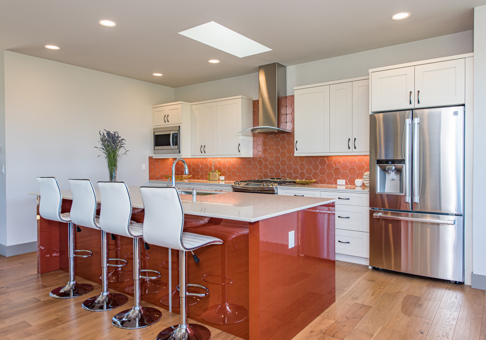 Foto på ett stort funkis vit kök, med en undermonterad diskho, skåp i shakerstil, vita skåp, bänkskiva i kvarts, stänkskydd i glaskakel, rostfria vitvaror, mellanmörkt trägolv, en köksö, brunt golv och orange stänkskydd